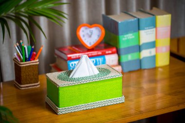 Tahta bir okuma masasının üzerinde bir mendil kutusu. Liften yapılmış bir mendil kutusu. Ananas yaprağı lifleri.