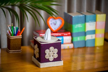 Tahta bir okuma masasının üzerinde bir mendil kutusu. Liften yapılmış bir mendil kutusu. Ananas yaprağı lifleri.