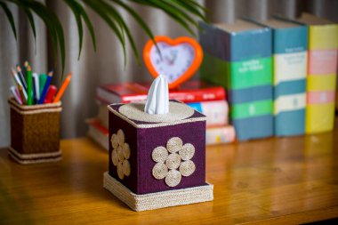 Tahta bir okuma masasının üzerinde bir mendil kutusu. Liften yapılmış bir mendil kutusu. Ananas yaprağı lifleri.