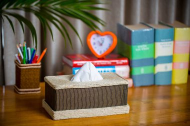 Tahta bir okuma masasının üzerinde bir mendil kutusu. Liften yapılmış bir mendil kutusu. Ananas yaprağı lifleri.