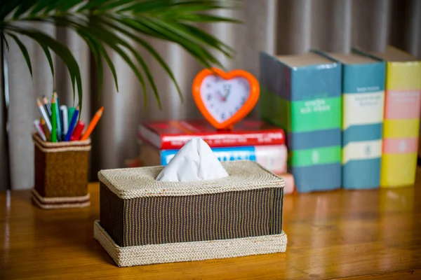 Tahta bir okuma masasının üzerinde bir mendil kutusu. Liften yapılmış bir mendil kutusu. Ananas yaprağı lifleri.