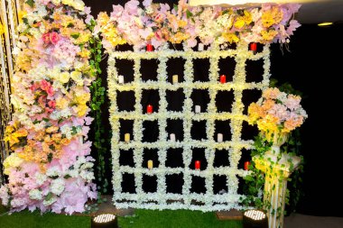 Yapay mumlar ve çiçek süslemeleriyle düğün sahnesi.