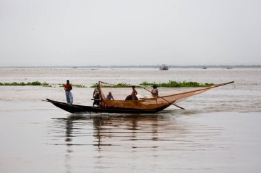 Bazı balıkçılar, Chandpur, Chandpur, Bangladeş 'teki Meghna Nehri' ndeki geleneksel balıkçı teknesinden uzun balık ağıyla balık yakalıyorlar..