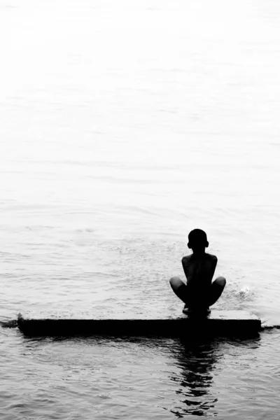 Nehir suyunda yıkanan ve eğlenen bir köy çocuğu. Güneş ışığına karşı görüntü. Siluet resmi.