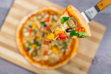 Yakın çekim ve tavuklu mantarlı jalapeno pizza dilimi ahşap kesme tahtasından alındı..