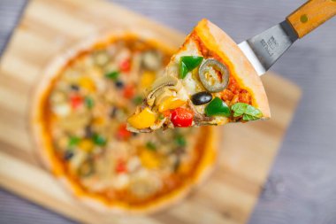 Yakın çekim ve tavuklu mantarlı jalapeno pizza dilimi ahşap kesme tahtasından alındı..