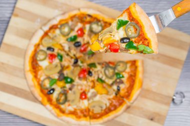 Yakın çekim ve tavuklu mantarlı jalapeno pizza dilimi ahşap kesme tahtasından alındı..