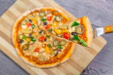 Yakın çekim ve tavuklu mantarlı jalapeno pizza dilimi ahşap kesme tahtasından alındı..