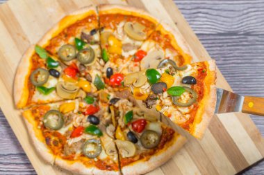 Yakın çekim ve tavuklu mantarlı jalapeno pizza dilimi ahşap kesme tahtasından alındı..