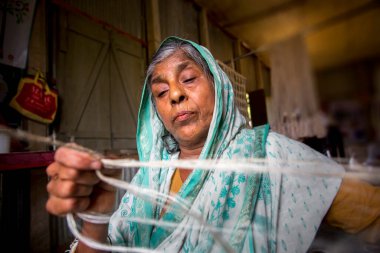 Yaşlı bir kadın, sıska elleriyle, Madhupur 'daki muz ağacı lifinden bir ip yapıyor..