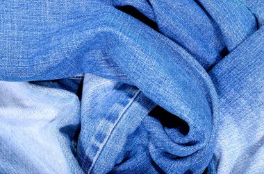 Buruşuk denim kumaş dokusu üzerinde yakın çekim. Kot pantolon üzerine arka plan olarak yakın çekim.