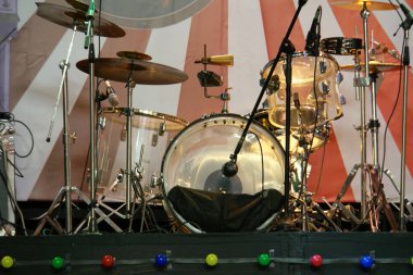 Perküsyon müzik enstrümanlarına yakın çekim. Sahnede bateri, gitar ve elektronik enstrümanlar var.                               