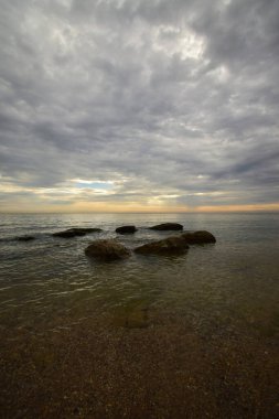  Hazar Denizi 'nin kıyısındaki Panorama Pembe-Turuncu gökyüzü, Kafkasya eteklerinde dalgalar ve gri bulutlar                              