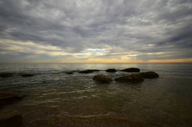  Hazar Denizi 'nin sabah manzarası pembe-turuncu gökyüzü, dalgalar ve kayalar Kafkasya eteklerinin eteklerinde                              
