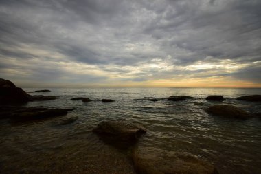 Yazın başında Kafkasya 'da pembe-sarı gökyüzü ve gri bulutlarla Hazar Denizi kıyıları ve uçurumları manzarası 