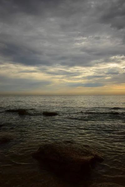 Yazın Kafkasya 'da kıyı ve sabah kayaları, pembe-sarı gökyüzü ve gri bulutlarla Hazar Denizi manzarası                               