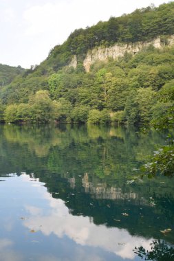 Kafkasya Dağları 'ndaki Cherek-Balkarian Geçidi' ndeki karst gölünün mavi sularının ve yeşil ağaçların manzarası                               