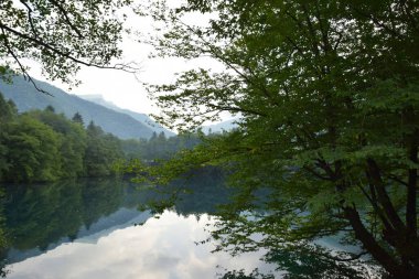 Yazın Kafkas Dağı 'ndaki Cherek-Balkarian Geçidi' nde yeşil ağaçlı bir karst ve mavi göl manzarası