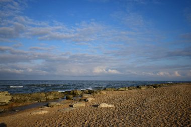  Doğu Kafkasya kıyısında dalgalar, kayalar ve mavi gökyüzü ile Hazar Denizi 'nin kumlu sahili.                              