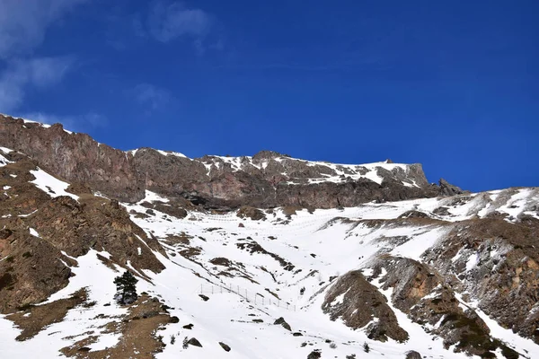Kuzey Kafkasya 'nın dağlarındaki Azau Vadisi' ndeki Elbrus Dağı 'nın eteğindeki karlı kayalık dağ sırasının ve mavi gökyüzünün görüntüsü                               