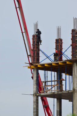 Kuzey Kafkasya 'nın eteklerindeki mavi gökyüzüne karşı inşaatçılar tarafından desteklenen ve beton dökülen iskelet.