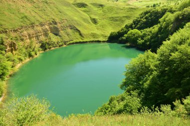  Kuzey Kafkasya dağlarında Kabardino-Balkaria 'nın Zolsk bölgesindeki yeşil bitki örtüsüyle çevrili karst buzul alp gölü Shadhurei Panoraması                              