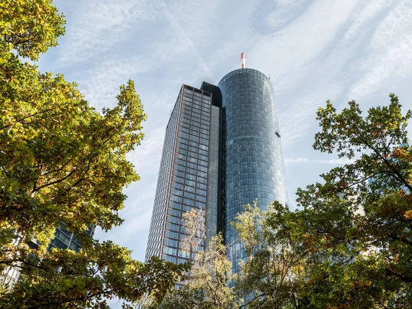 Main Tower Skyscraper low angle with trees in forefront on a sunny day, Frankfurt, Hessen, Germany