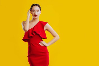 Kırmızı dresover sarı arka planda poz güzel kadın.