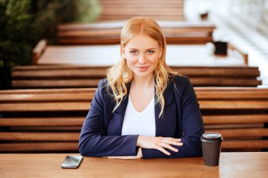 Restoran terasında, odaklanmamış bir geçmişi olan akıllı bir telefonla mesajlaşan kız.
