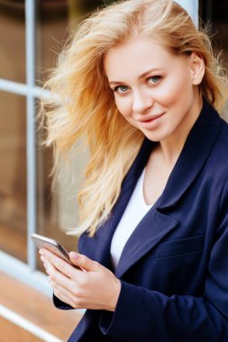 Kadar neşeli genç bayan Trendy kıyafeti, onun cep telefonu iken yürüme şehir sokak Holding kapatın