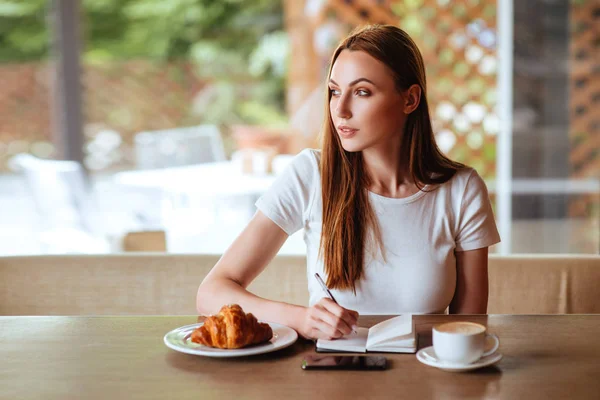 Hermosa Chica Cafetería Con Sabrosa Escritura Capuchino Cuaderno Blanco —  Fotos de Stock