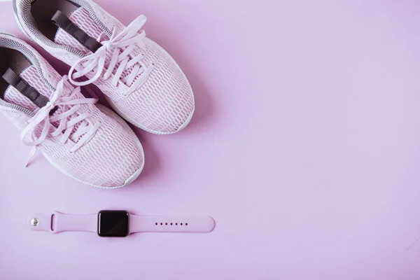 Violet sneakers and watches. Lay flat style Pink background.
