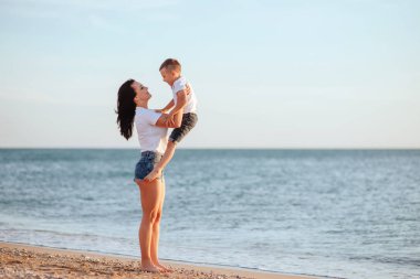 Genç Anne ile deniz kenarında tatil zevk iki küçük oğlu okyanus plaj boyunca. Annelik.