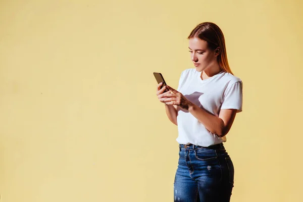 Portrait Smiling Beautiful Blonde Girl White Shirt Jeans Smartphone Yellow — Stock Photo, Image