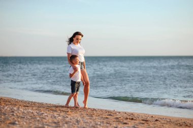 Genç Anne ile deniz kenarında tatil zevk iki küçük oğlu okyanus plaj boyunca. Annelik.