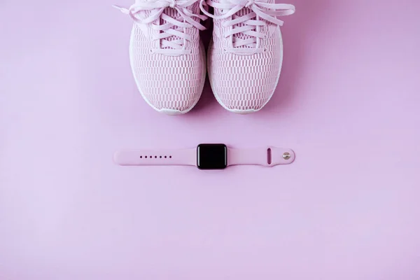 Violet sneakers and watches. Lay flat style Pink background.