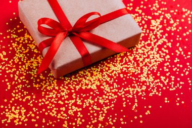 Çok renkli konfeti ile renkli arka plan üzerinde kırmızı yay ile kutusu mevcut. Düz yatıyordu stili.