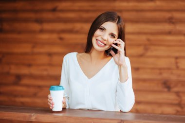 Onun smartphone kullanarak ve şehir kafede kahve içme güzel genç kadın