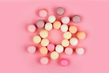 Pembe bir arka plan üzerinde üstten görünüm renkli macaron veya acıbadem kurabiyesi. seçici odak. Düz yatıyordu