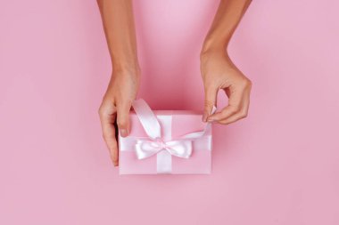 kahverengi hediye kutusu ile yer pembe pastel renkli arka plan üzerinde tutan üstten görünüm el kadın.