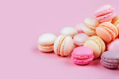 Pembe bir arka plan üzerinde renkli macarons satırı. Üstten görünüm. Afiş.