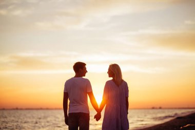 Işıkları günbatımı sahil üzerinde genç mutlu çift.