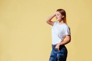 Beyaz t-shirt ve jeans sarı arka plana karşı gülümseyen güzel sarışın kız portresi.