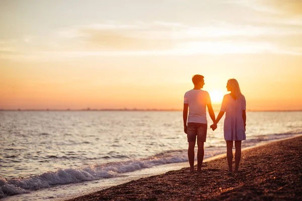 Young happy couple on seashore in the lights of sunset.