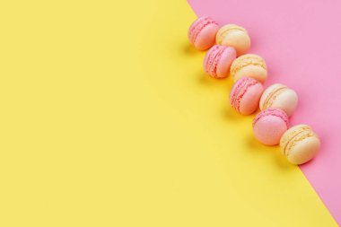 Lezzetli macarons sarı - pembe bir arka plan üzerinde çapraz iki üçgen içine bölünmüş