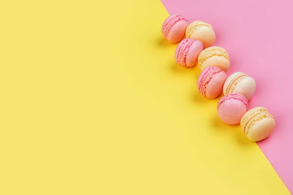 Smaczny Macarons Żółto Różowym Tle Ukośnie Dwa Trojkaty — Zdjęcie stockowe