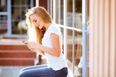 Açık havada Smartphone kullanarak çekici gülümseyen kadın. Lefestyle kavramı