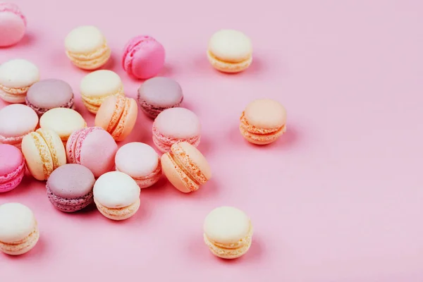 Different types of macaroons on pink background. Sweet and colourful french macaroons.