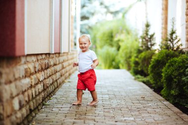 Komik sarışın yürümeye başlayan çocuk yaz bahçesinde. Rahat yaşam tarzı fotoğraf.