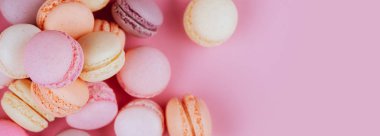 Pembe bir arka plan üzerinde renkli macarons satırı. Üstten görünüm. Afiş.